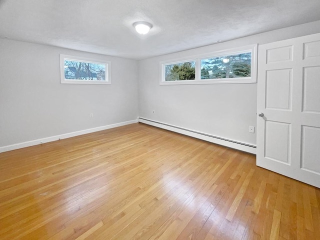 empty room with light wood-type flooring and baseboard heating