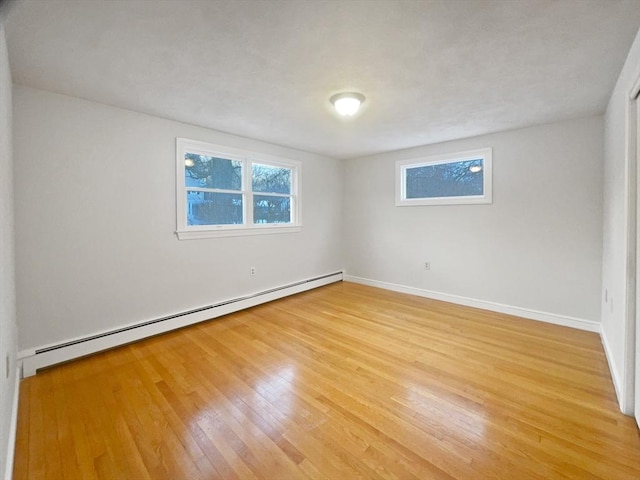 unfurnished room with a baseboard heating unit and hardwood / wood-style floors