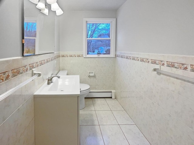 bathroom with toilet, vanity, tile walls, tile patterned flooring, and baseboard heating