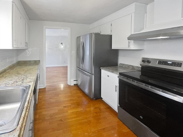 kitchen with wall chimney range hood, sink, light wood-type flooring, appliances with stainless steel finishes, and white cabinets