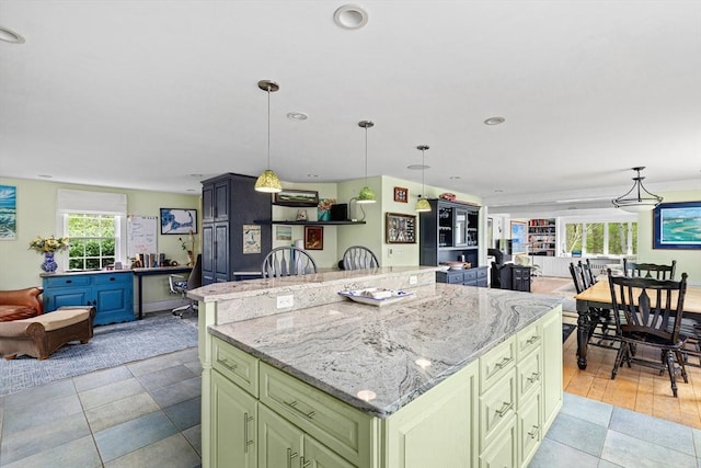 kitchen featuring decorative light fixtures, light stone countertops, and a kitchen island