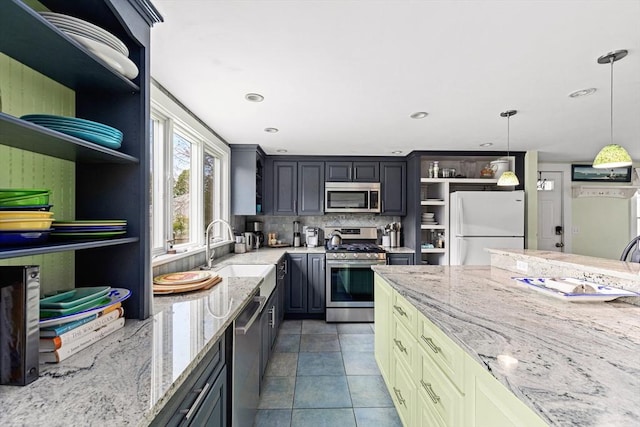 kitchen with pendant lighting, sink, light stone countertops, and appliances with stainless steel finishes