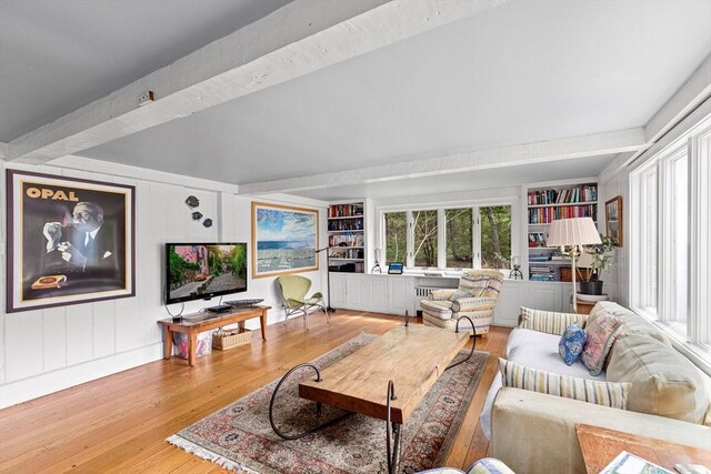 living room with beam ceiling, built in features, and light wood-type flooring