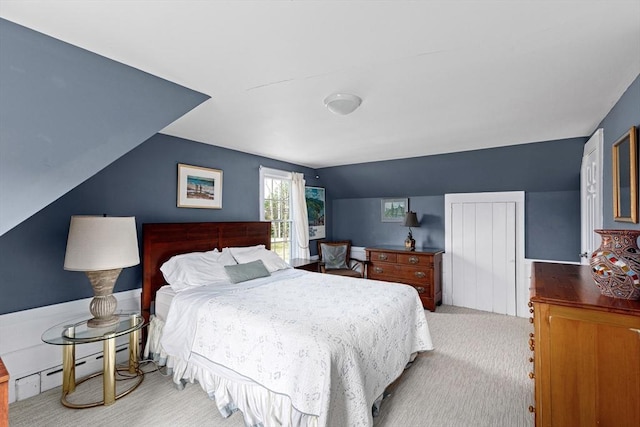 bedroom featuring vaulted ceiling, a baseboard heating unit, and light colored carpet