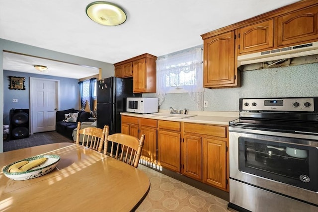 kitchen featuring tasteful backsplash, sink, electric range, and black fridge