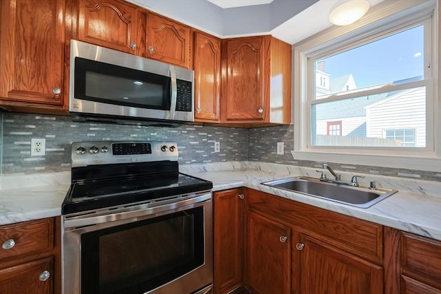 kitchen featuring light stone countertops, appliances with stainless steel finishes, sink, and decorative backsplash