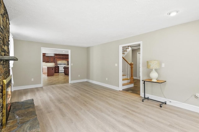 184 Burlingame Rd, Charlton, MA 01507 - unfurnished living room with stairs, a large fireplace, baseboards, and light wood-style floors