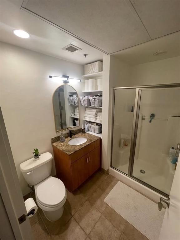 130 John Unit 213, Lowell, MA 01852 - bathroom with a stall shower, vanity, toilet, and tile patterned flooring
