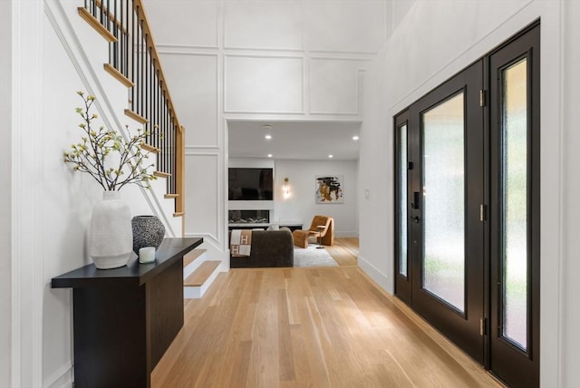 foyer entrance featuring baseboards, light wood finished floors, stairway, and a decorative wall