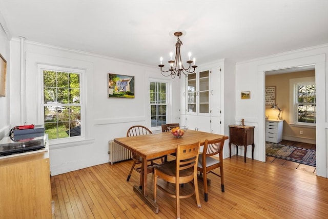 dining room with a chandelier, light wood-type flooring, healthy amount of natural light, crown molding, and radiator