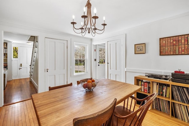 dining area featuring a chandelier, healthy amount of natural light, hardwood / wood-style floors, and crown molding