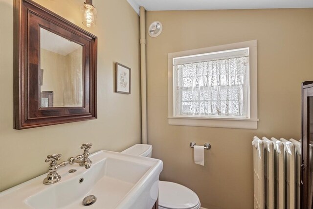 bathroom with radiator, a sink, and toilet