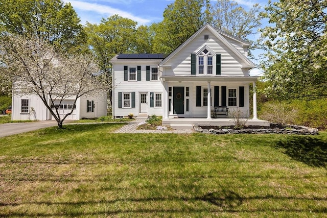 view of front of house featuring covered porch, roof mounted solar panels, and a front yard