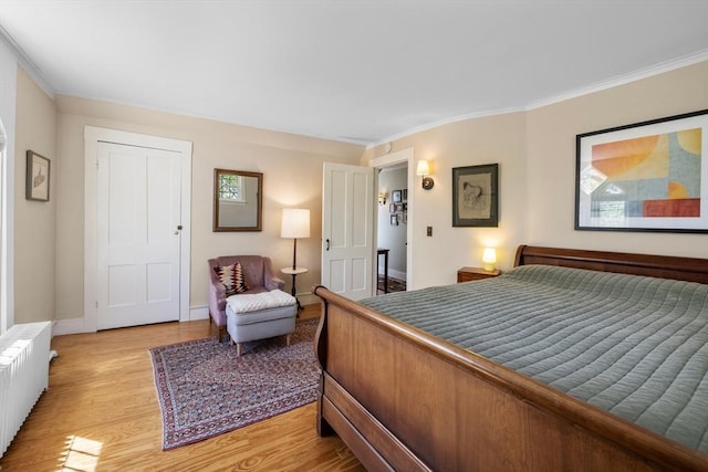 bedroom with radiator heating unit, light wood-style flooring, crown molding, and baseboards