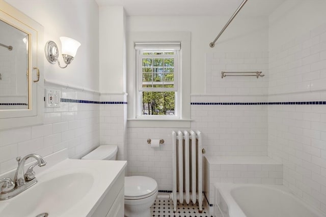 bathroom featuring radiator, tile walls, toilet, vanity, and wainscoting