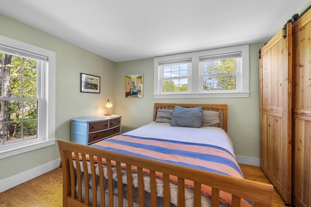 bedroom featuring baseboards, light wood-style floors, and a barn door