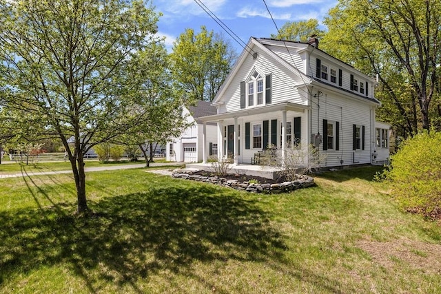 rear view of property with a chimney, an attached garage, a porch, and a yard