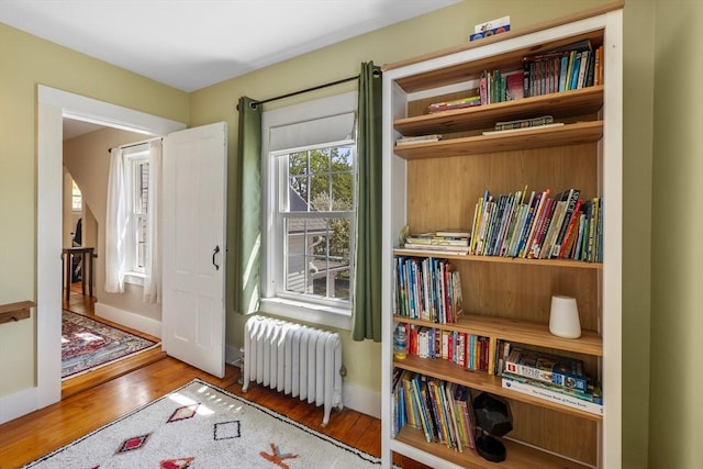 living area with radiator, wood finished floors, and baseboards