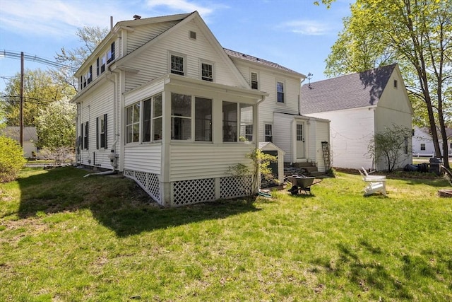 back of property with a lawn and a sunroom