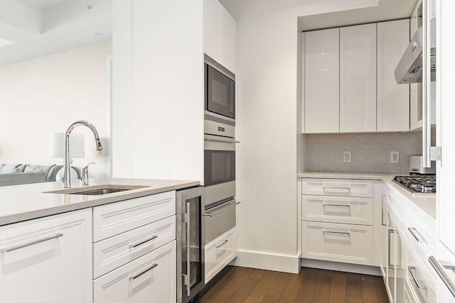 kitchen featuring oven, beverage cooler, a sink, stainless steel gas stovetop, and built in microwave