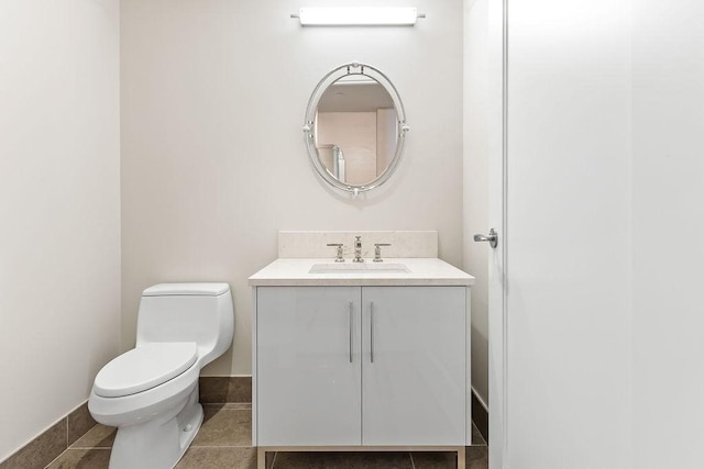 bathroom featuring vanity, toilet, baseboards, and tile patterned flooring