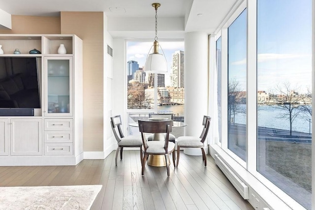 dining space with expansive windows, visible vents, a view of city, and hardwood / wood-style flooring