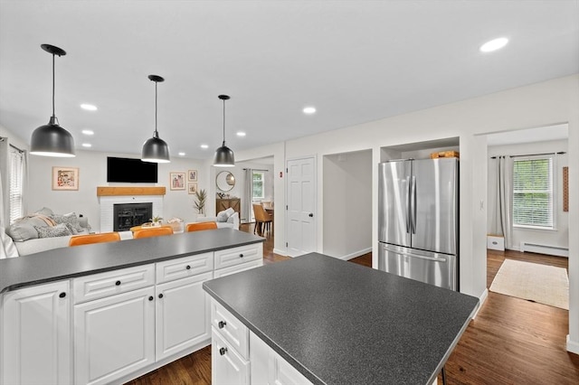 10 Old Broad St, Holden, MA 01522 - kitchen featuring freestanding refrigerator, a baseboard radiator, dark countertops, a center island, and a brick fireplace