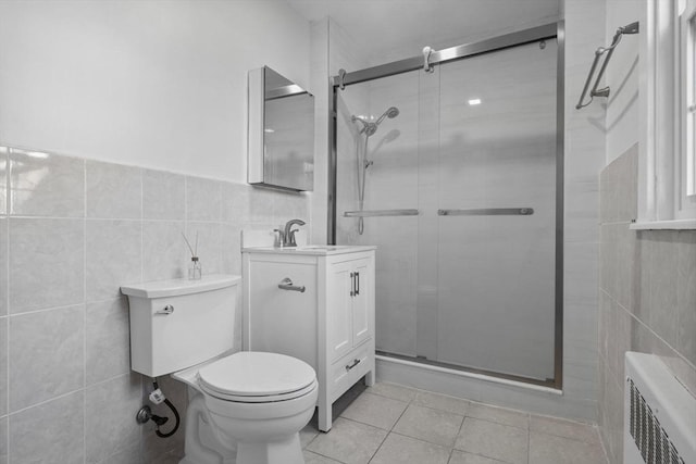 bathroom with radiator, an enclosed shower, vanity, tile walls, and tile patterned flooring