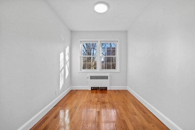 spare room with radiator heating unit and light wood-type flooring