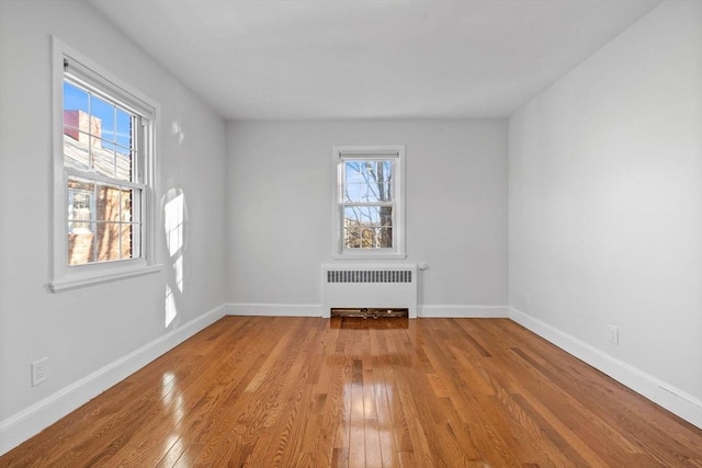 unfurnished room featuring radiator heating unit and light hardwood / wood-style flooring