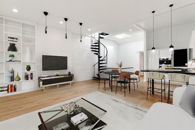 living room featuring a skylight, built in shelves, and light hardwood / wood-style flooring