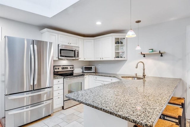 kitchen with white cabinetry, a peninsula, stainless steel appliances, and a sink