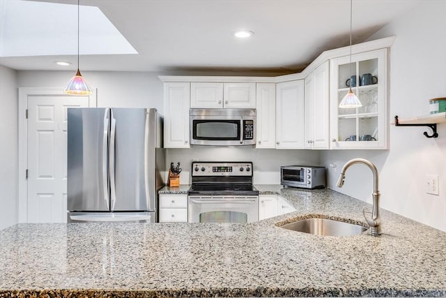 kitchen featuring a sink, light stone counters, white cabinetry, and stainless steel appliances