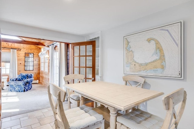 dining room with wooden walls and stone finish floor