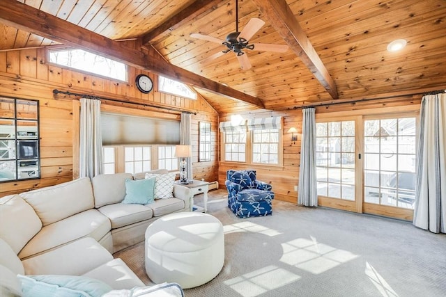 living area with lofted ceiling with beams, carpet floors, wooden walls, and a healthy amount of sunlight