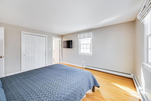 bedroom with a baseboard heating unit, baseboards, and wood finished floors