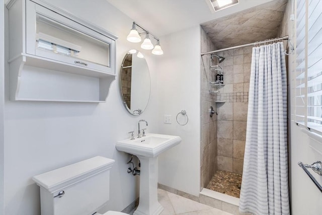 bathroom featuring tile patterned floors, toilet, visible vents, and a tile shower