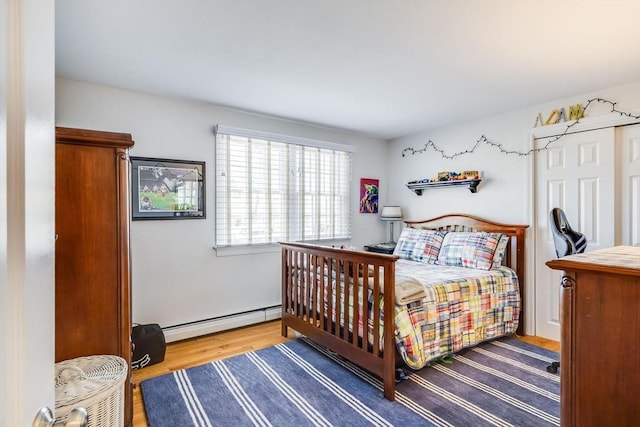 bedroom featuring wood finished floors and a baseboard radiator