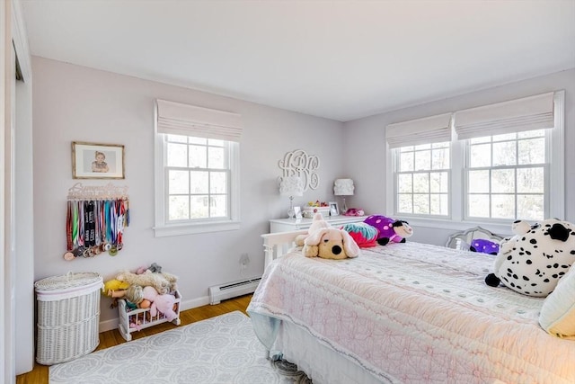 bedroom featuring a baseboard radiator, baseboards, and wood finished floors