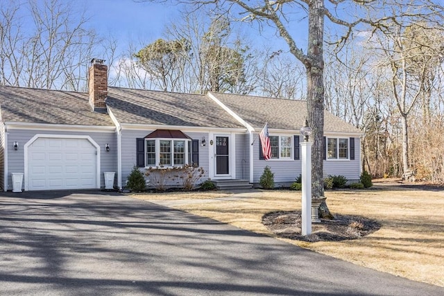 ranch-style house with aphalt driveway, a chimney, a garage, and roof with shingles