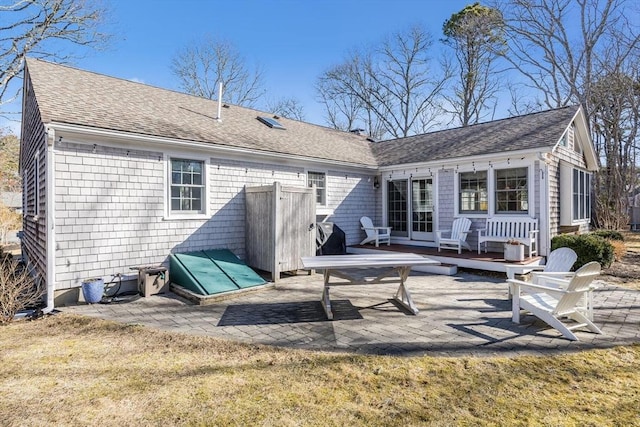 rear view of house featuring a patio area, a yard, a shingled roof, and a deck