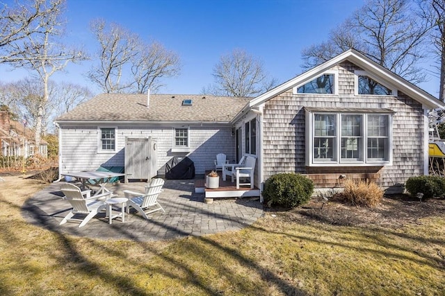 rear view of house with a yard, roof with shingles, and a patio area