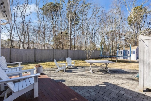 deck featuring a fenced backyard, a patio area, and a trampoline