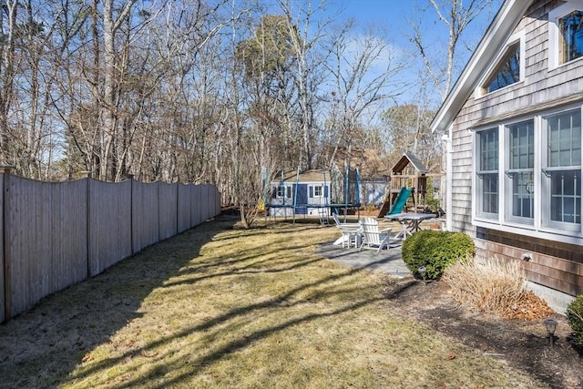 view of yard with a patio area, a trampoline, a fenced backyard, and a playground