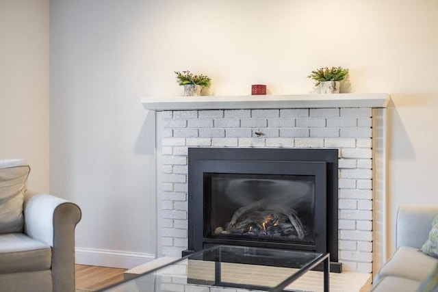 interior details with wood finished floors, a fireplace, and baseboards