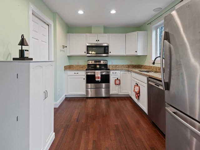 kitchen featuring light stone counters, appliances with stainless steel finishes, white cabinetry, and sink