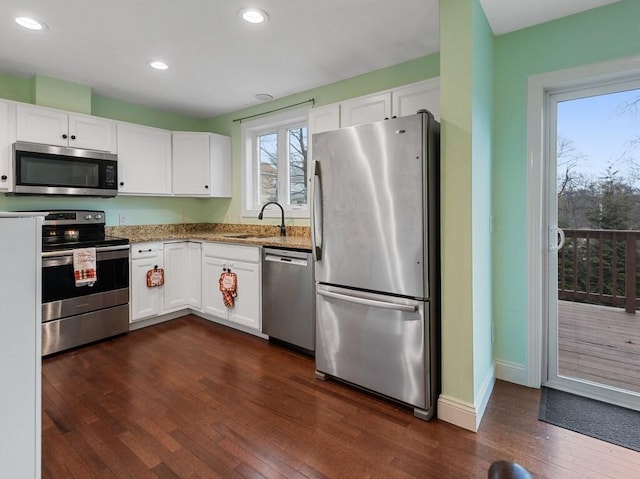 kitchen with sink, white cabinetry, light stone counters, and appliances with stainless steel finishes