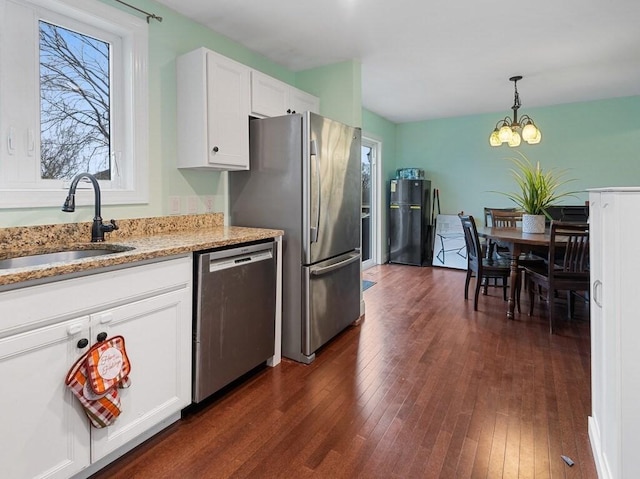 kitchen featuring a chandelier, decorative light fixtures, stainless steel appliances, white cabinets, and sink