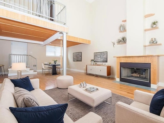 155 Brookline Unit 2, Cambridge, MA 02139 - living area featuring wood finished floors, a fireplace with flush hearth, built in shelves, baseboards, and a towering ceiling