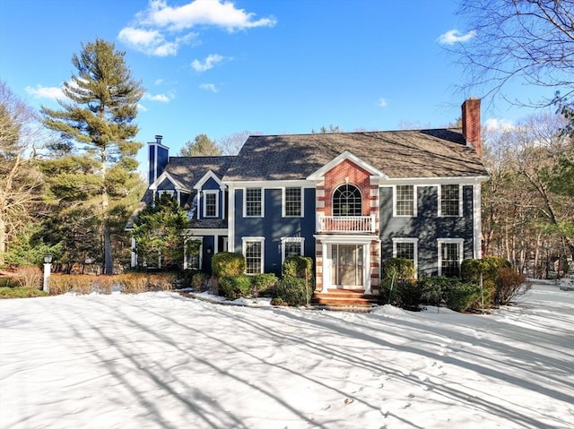 view of front facade featuring a chimney and a balcony